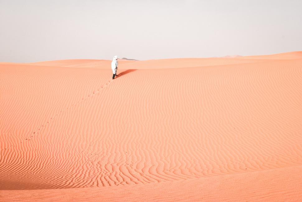 Free Image of Lone Person Walking Across a Large Sand Dune 