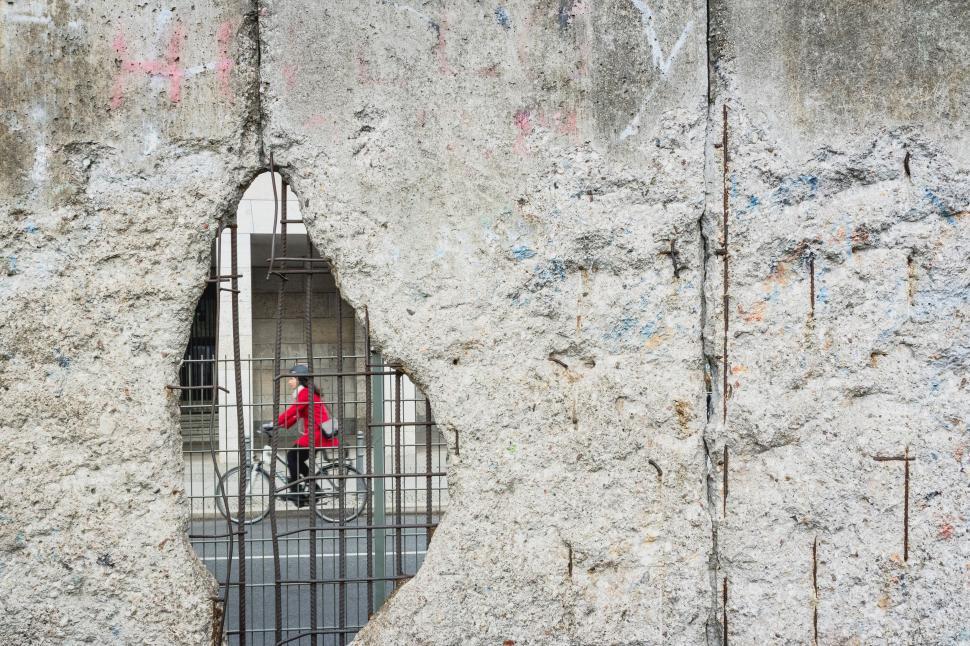 Free Image of Man Riding Bike Through Hole in Concrete Wall 