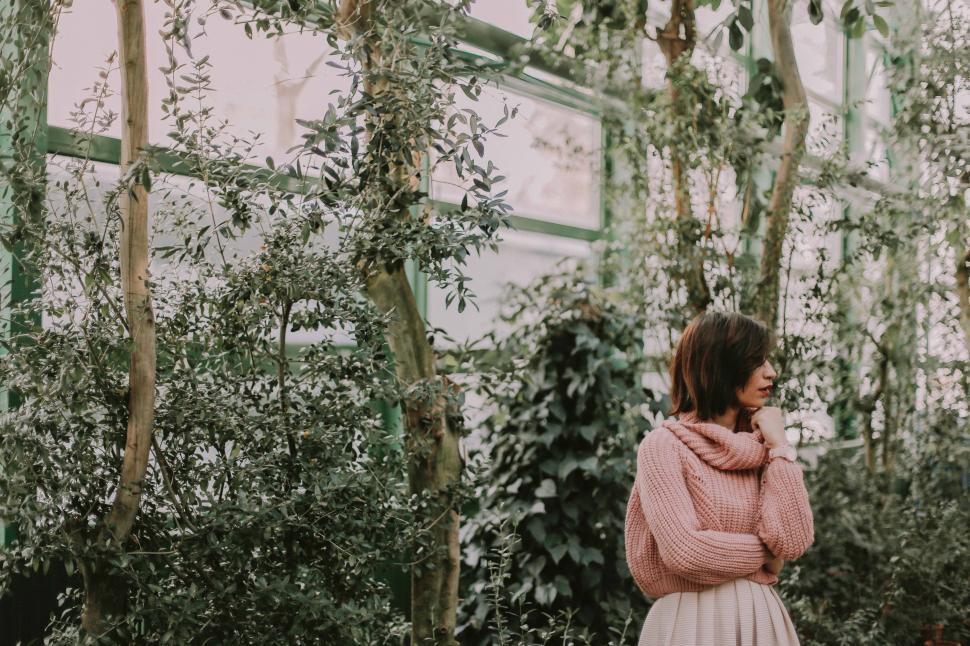 Free Image of Woman in Pink Sweater Standing in Greenhouse 