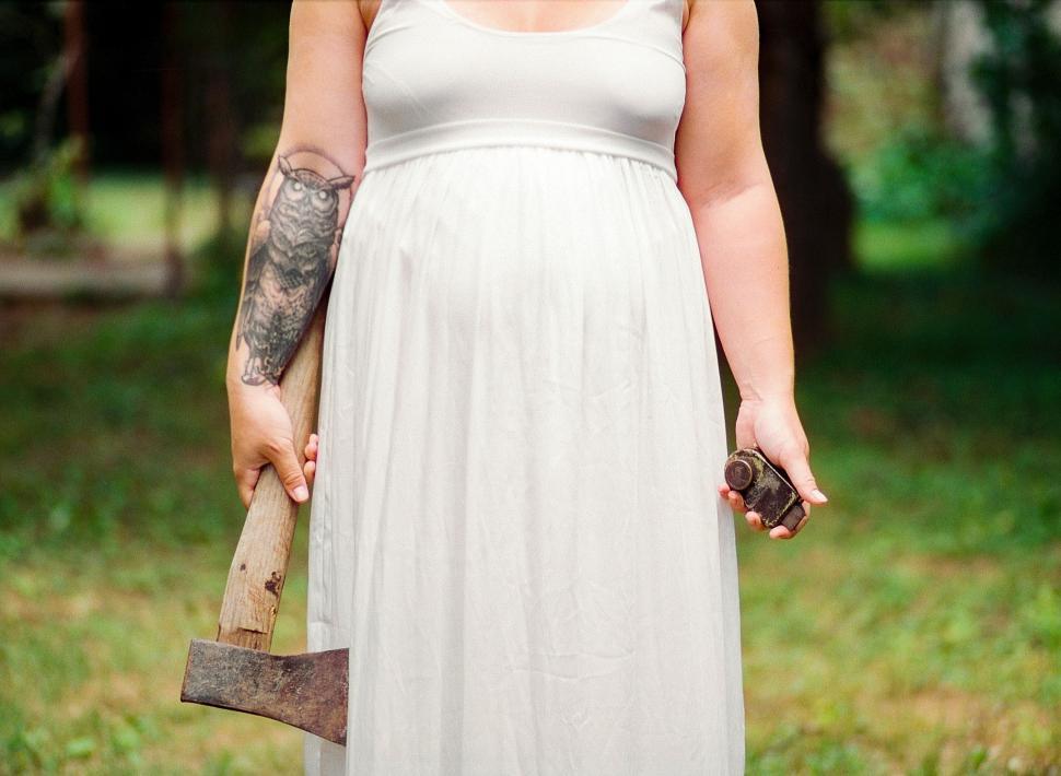 Free Image of Pregnant Woman in White Dress Holding Hammer 