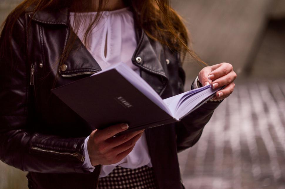 Free Image of Woman in Black Leather Jacket Holding Book 