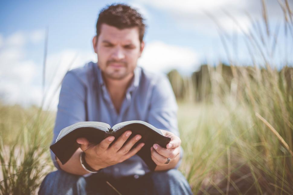 Free Image of Man Sitting in Grass Reading Book 