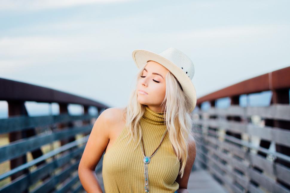 Free Image of Woman Wearing Hat Standing on Bridge 