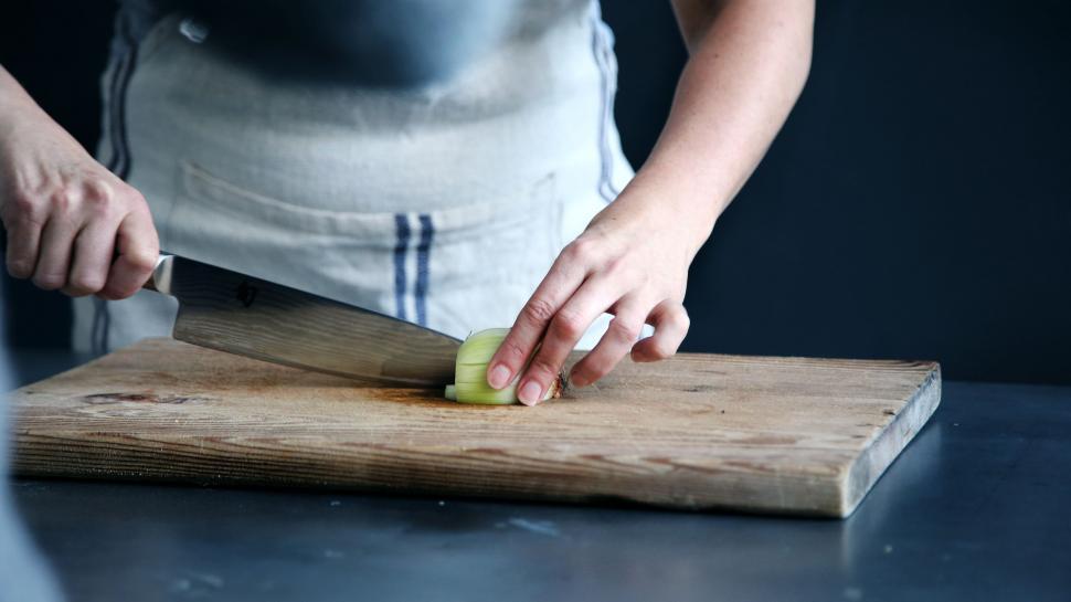 Free Image of Person in Apron Chopping Vegetables on Cutting Board 