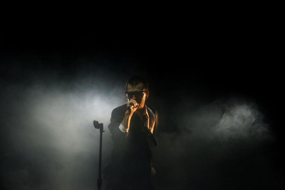 Free Image of Man Holding Microphone in the Dark 