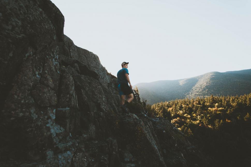 Free Image of Man Standing on Top of a Large Rock 