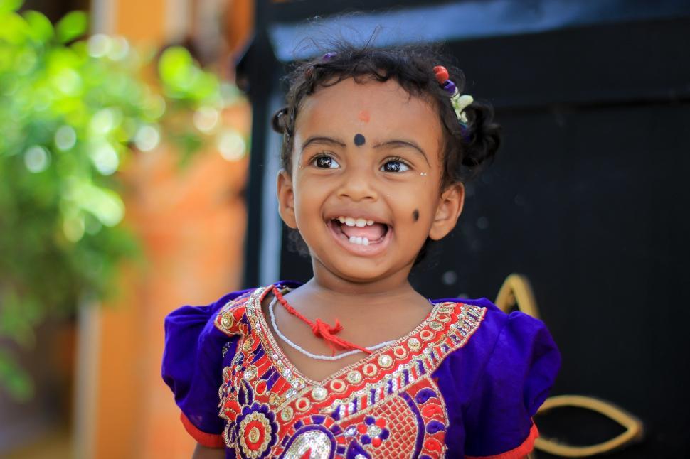 Free Image of Little Girl in Colorful Dress Smiling 