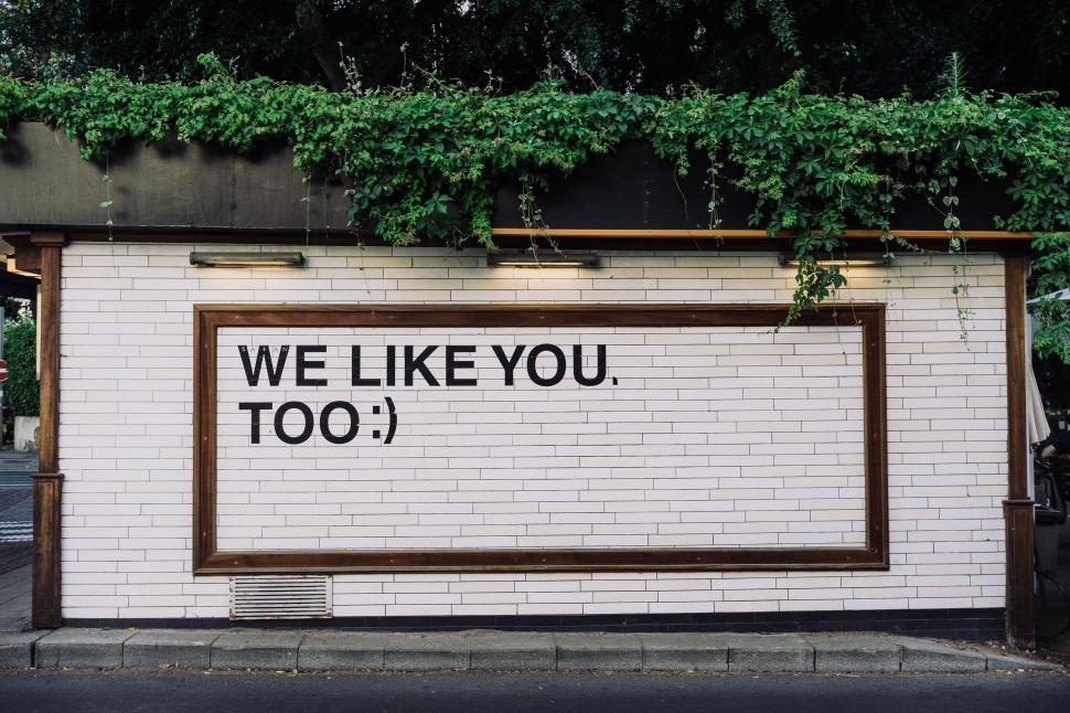 Free Image of White Brick Wall With We Like You Too Sign 