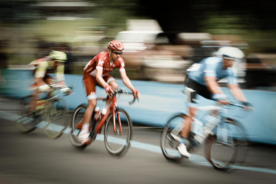 Free Image of Blurry Photo of Three Bicyclists Riding Down a Road 