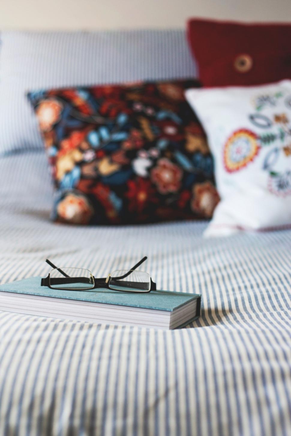 Free Image of Book Resting on Bed Beside Pillows 