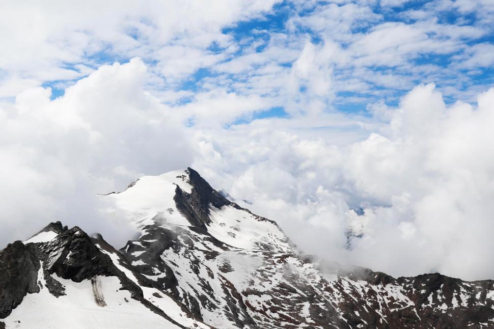 Free Image of Snow-Covered Mountain With Clouds in the Sky 