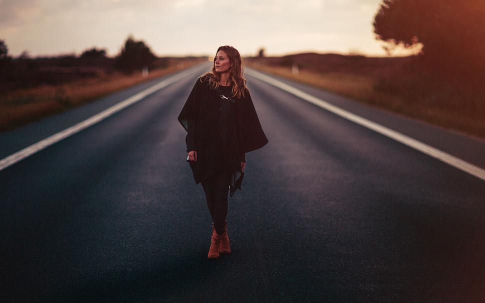 Free Image of Woman Walking Down the Middle of a Road 