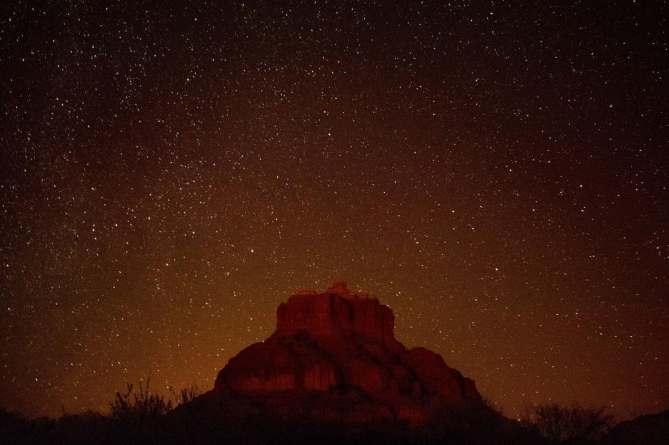 Free Image of Night Sky With Stars Above a Rocky Outcropping 