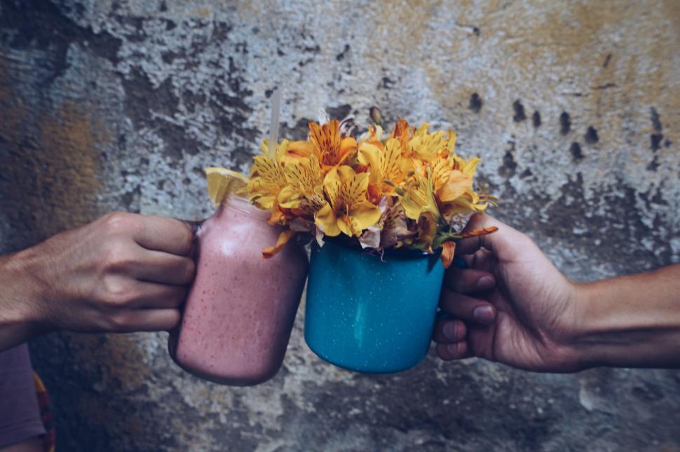 Free Image of Two Hands Holding a Blue Vase With Yellow Flowers 