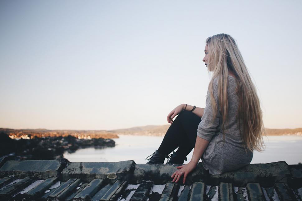 Free Image of Woman Sitting on Roof Next to Water 