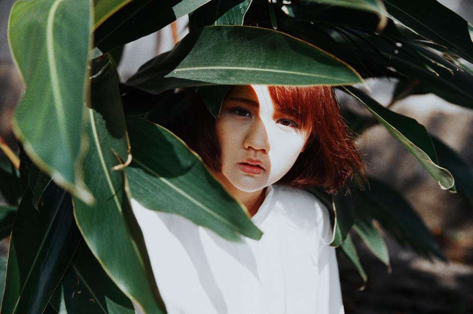 Free Image of Woman With Red Hair Hiding Behind Plant 
