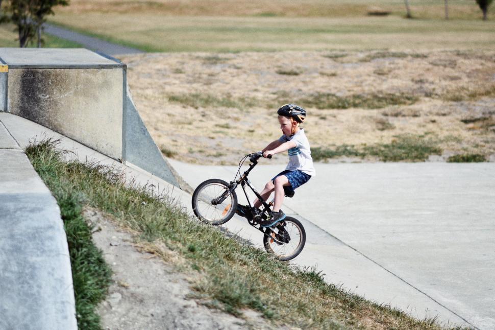 Free Image of Young Boy Riding a Bike Up a Ramp 