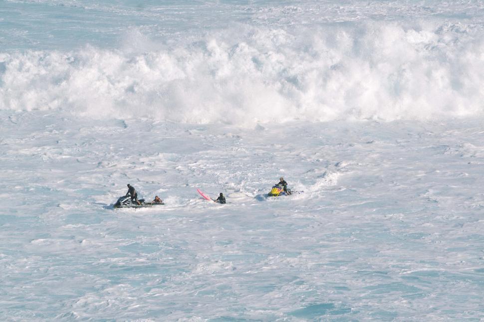 Free Image of Group of People Riding on Top of a Wave in the Ocean 