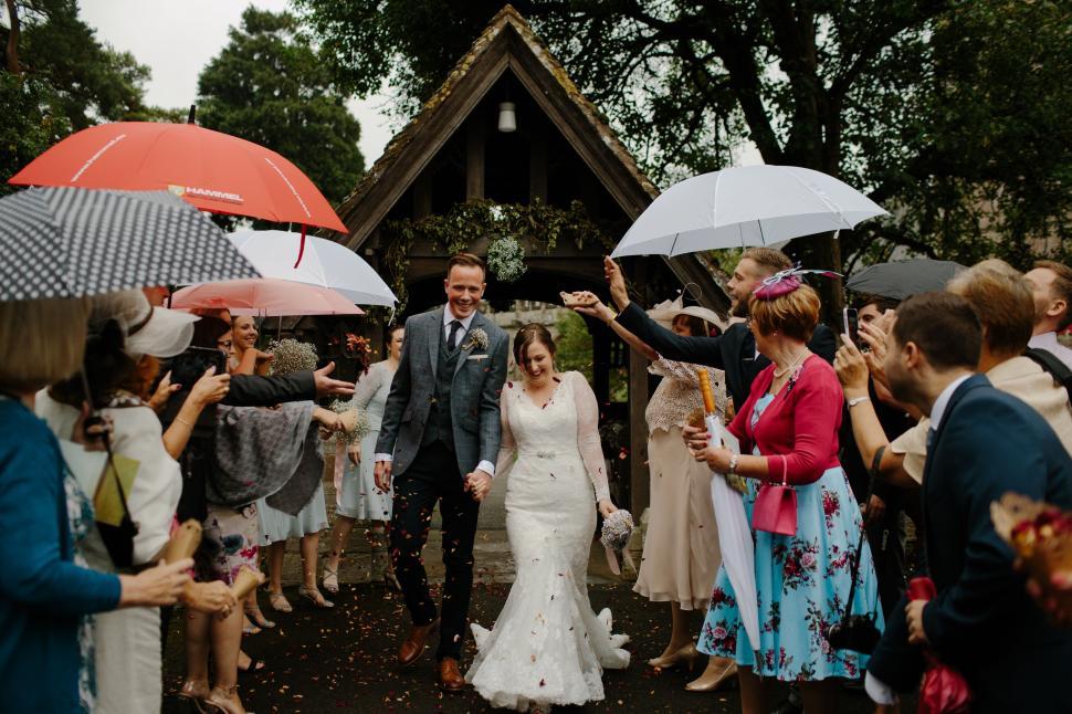 Free Image of Bride and Groom Walking Through Group of People Holding Umbrellas 