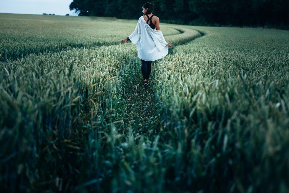 Free Image of Woman Walking Through a Field of Tall Grass 