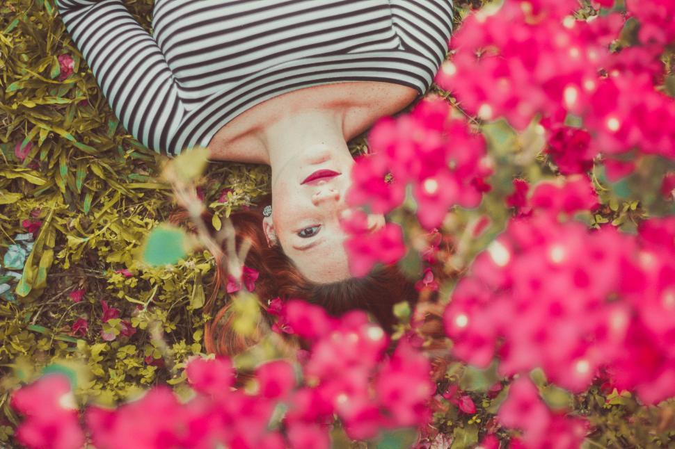 Free Image of Woman Laying on Ground Surrounded by Pink Flowers 