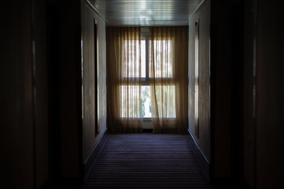Free Image of Dark Hallway Leading to Window With Sheer Curtains 