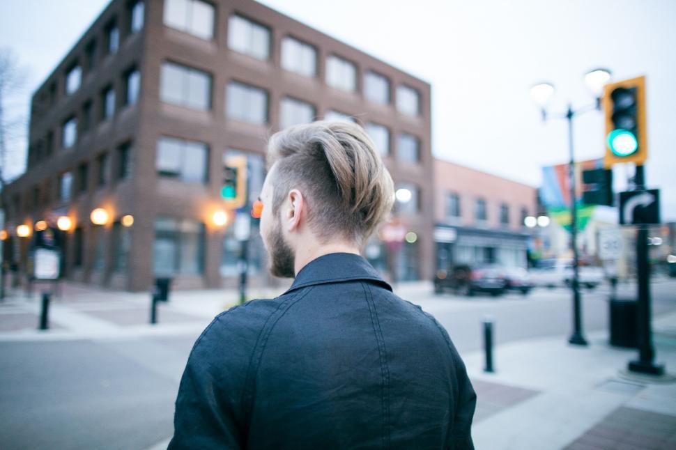 Free Image of Man With Bun in Hair Standing on Street Corner 