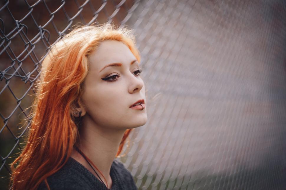 Free Image of Woman With Red Hair Standing Next to Fence 