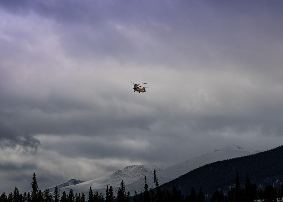 Free Image of Helicopter Flying Through Cloudy Sky Over Forest 