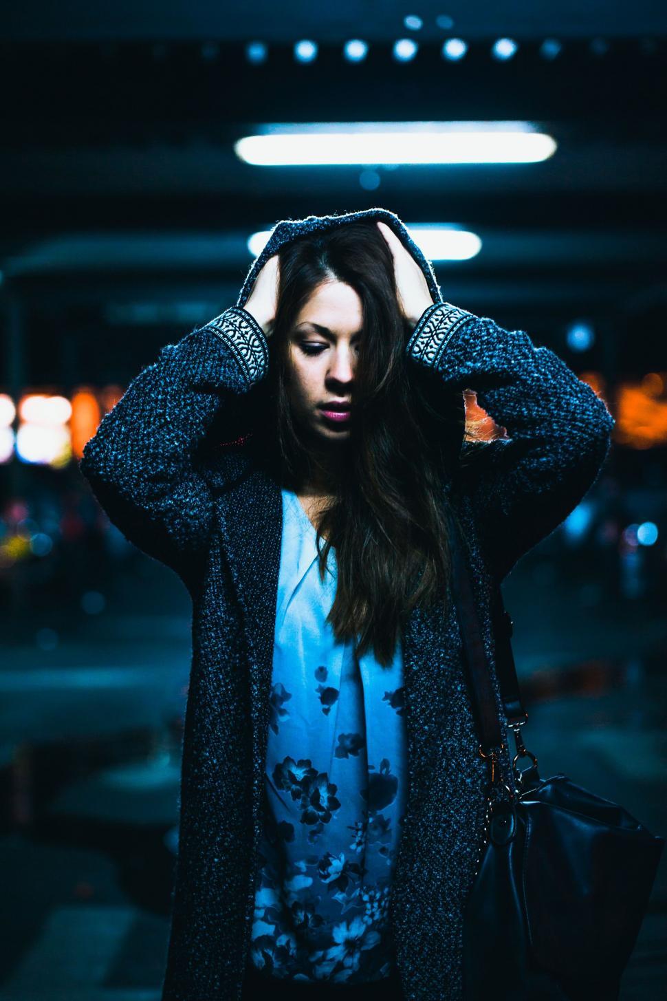 Free Image of Woman Standing in Parking Garage Holding Her Head 
