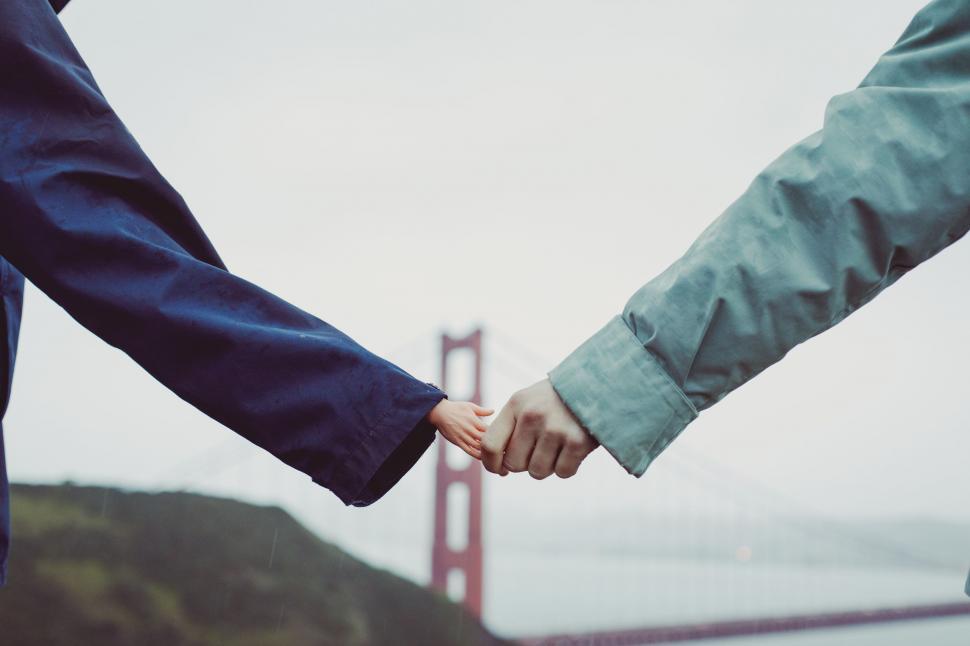 Free Image of Two People Holding Hands in Front of the Golden Gate Bridge 