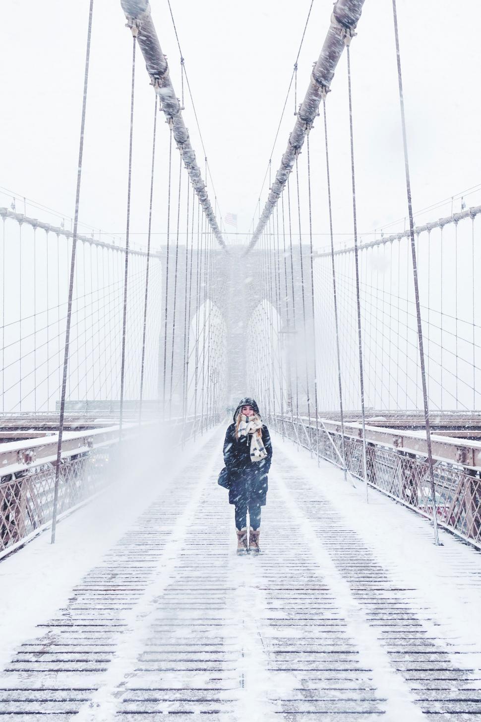Free Image of Woman Walking Across Snowy Bridge 