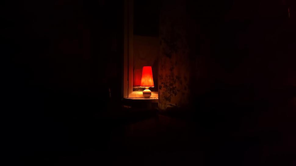 Free Image of Red Lamp Illuminating Table in Dark Room 
