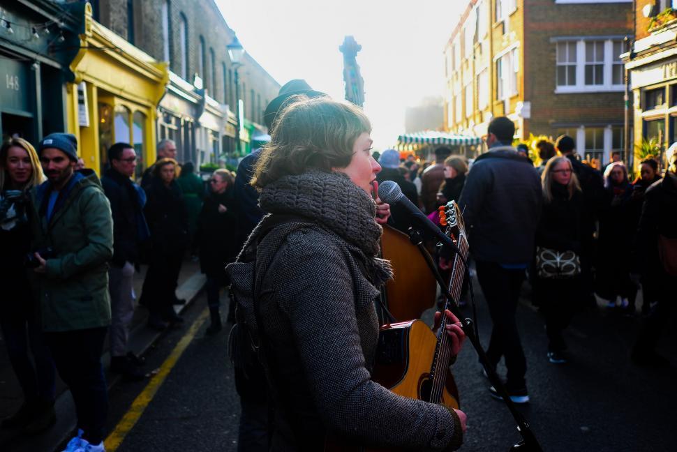 Free Image of Woman Playing Guitar in Crowded Street 