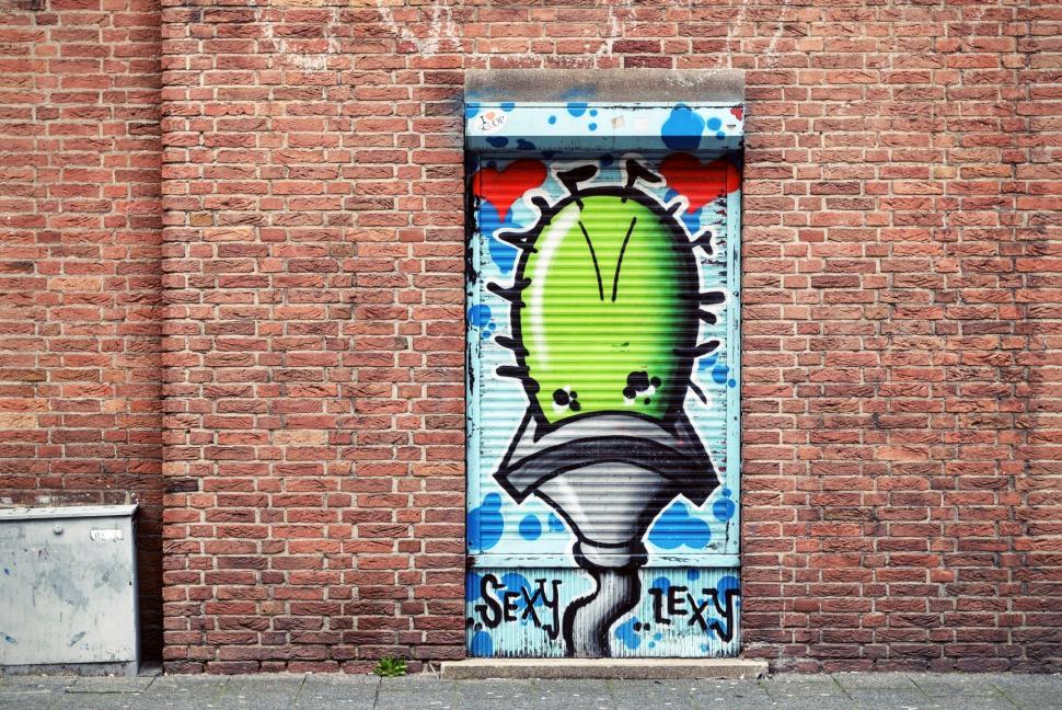 Free Image of Green Door With Graffiti Against Brick Wall 