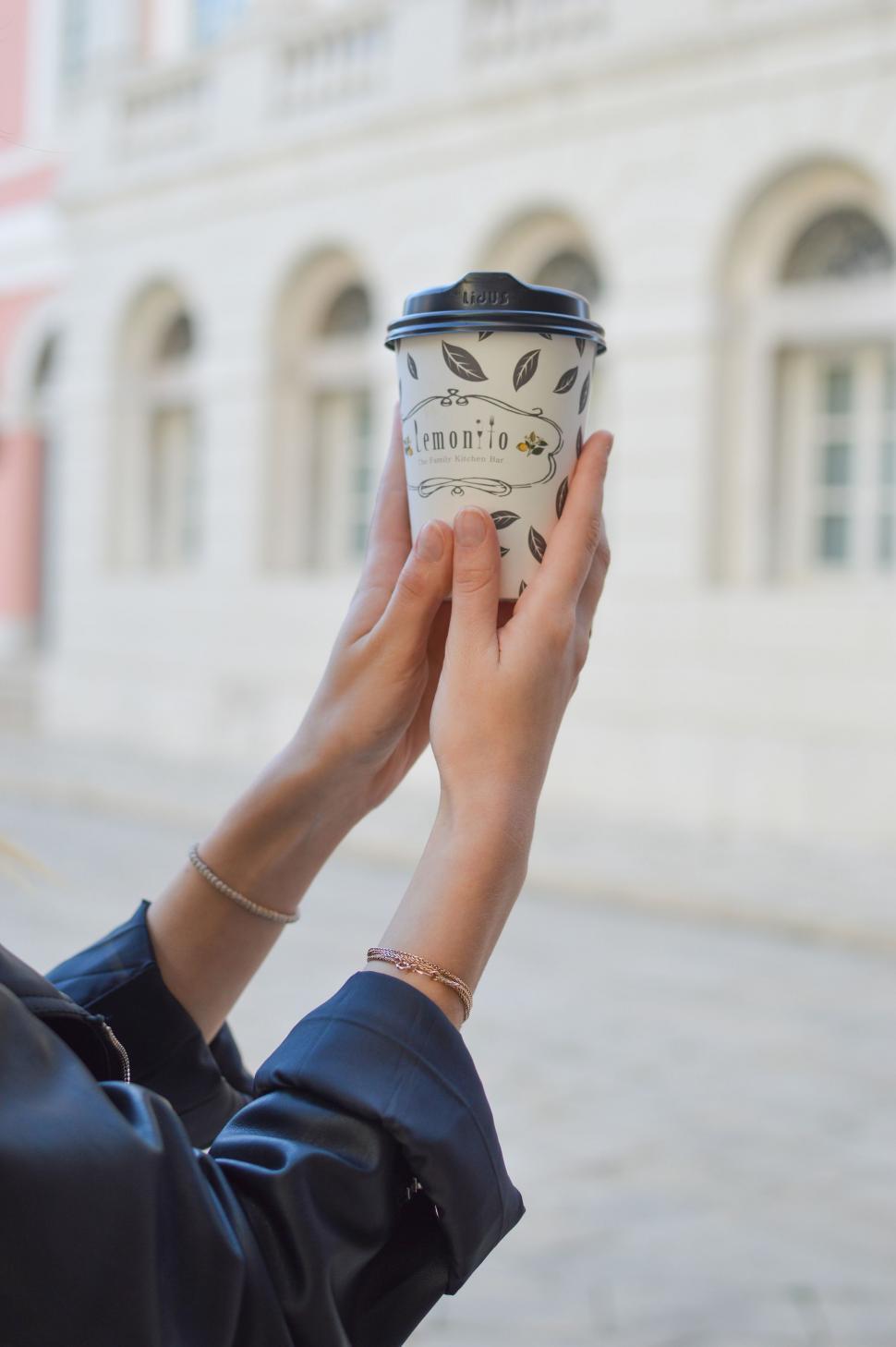 Free Image of Woman Holding a Cup of Coffee in Front of Building 