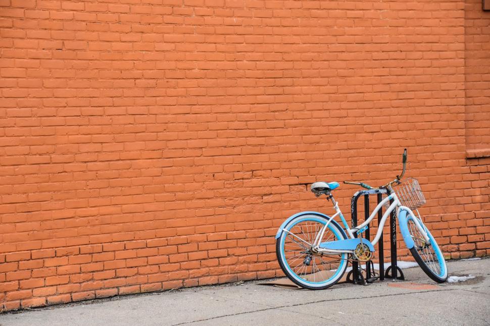 Free Image of Blue and White Bicycle Leaning Against Brick Wall 