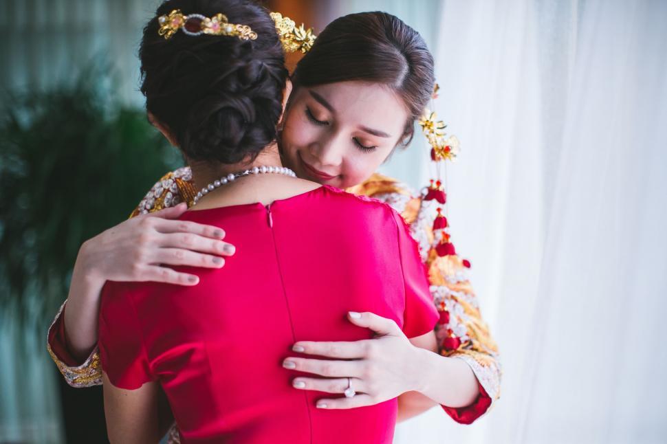 Free Image of Woman in Red Dress Hugging Another Woman 