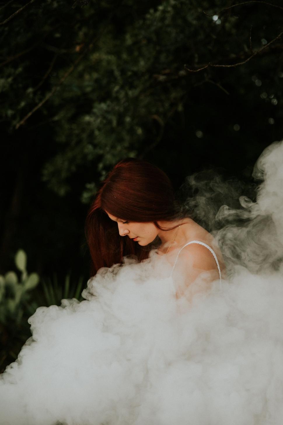 Free Image of Woman in White Dress Standing in Smoke 