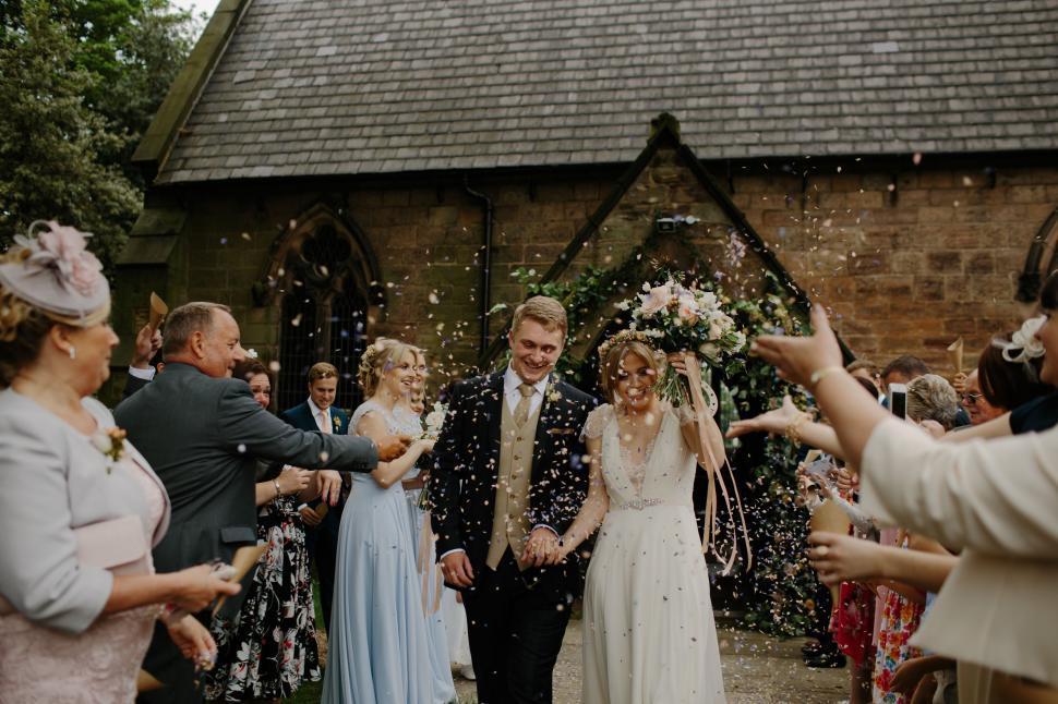 Free Image of Bride and Groom Walk Down Aisle Amid Confetti Shower 