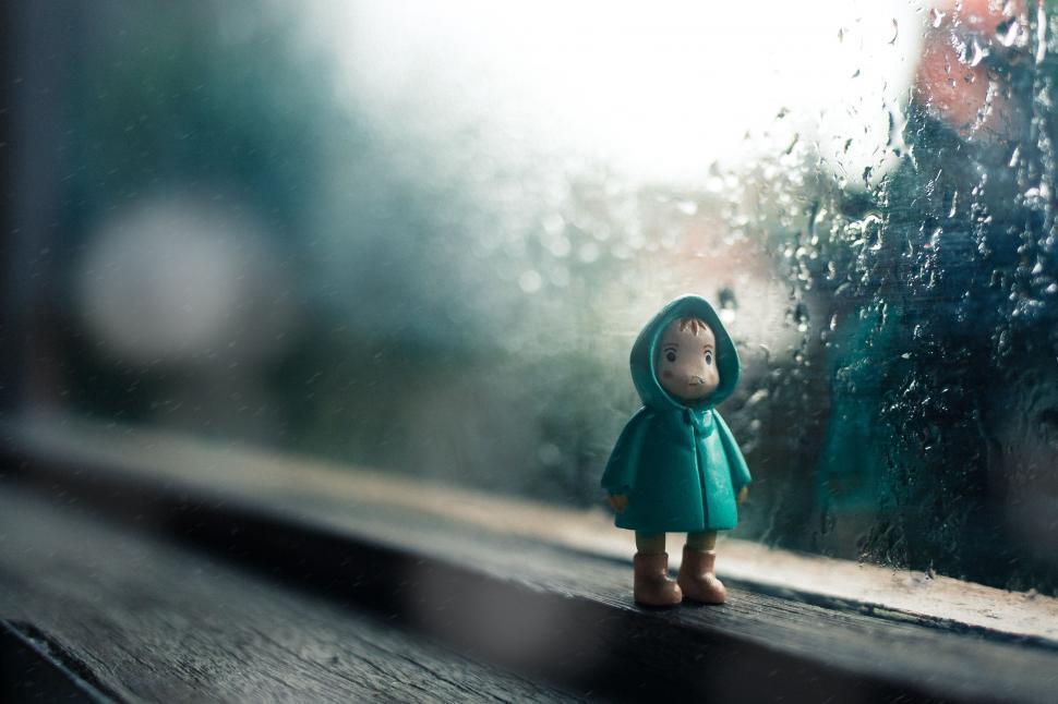 Free Image of Small Doll Standing in Front of Rainy Window 