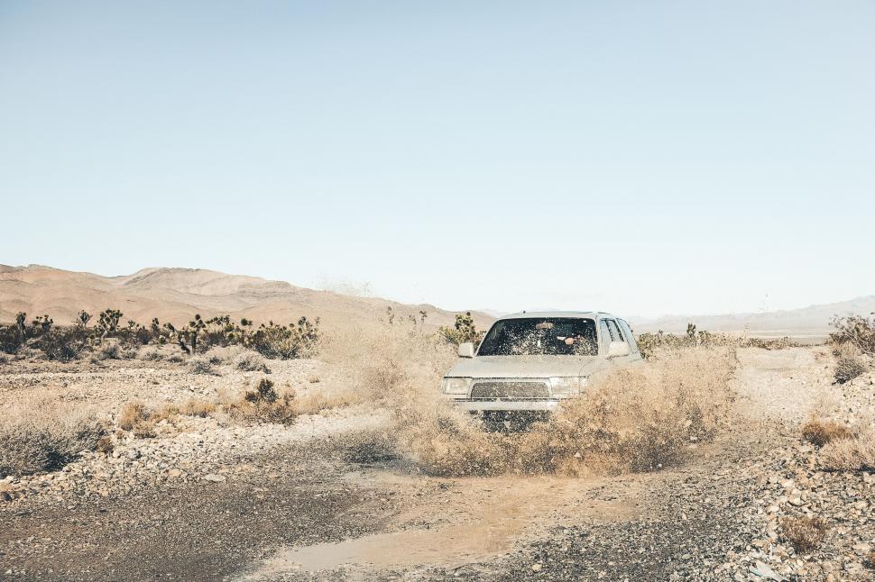Free Image of White Truck Driving Through Desert Filled With Dirt 