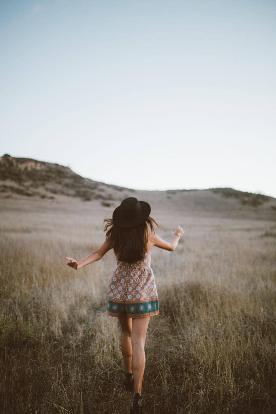 Free Image of Young Girl Walking Through a Field of Tall Grass 