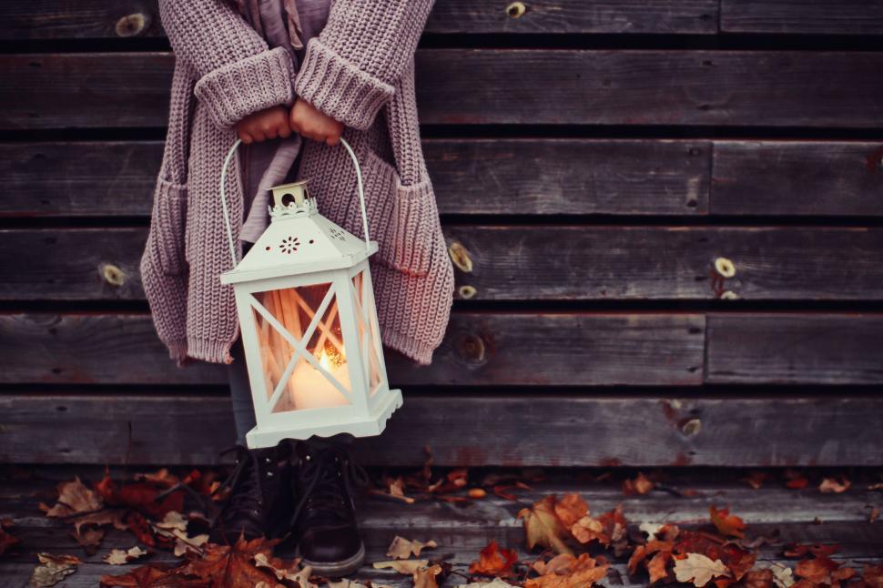 Free Image of Woman Holding Lantern in Front of Wooden Wall 