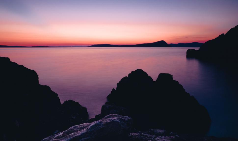 Free Image of Sunset Over Water With Rocks in Foreground 