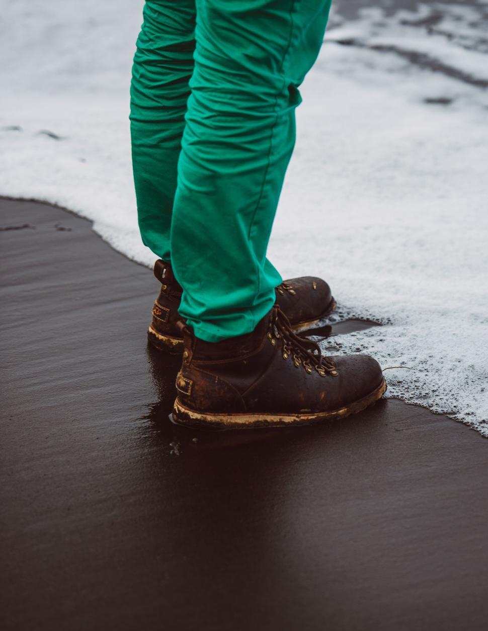 Free Image of Person in Green Pants Standing on Wet Surface 