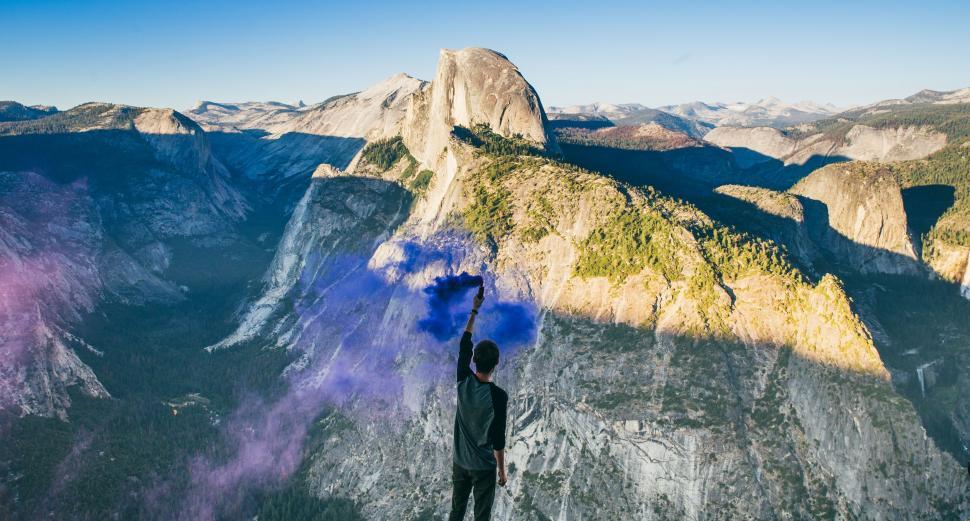 Free Image of Man Standing on Mountain Holding Blue Smoke Bomb 