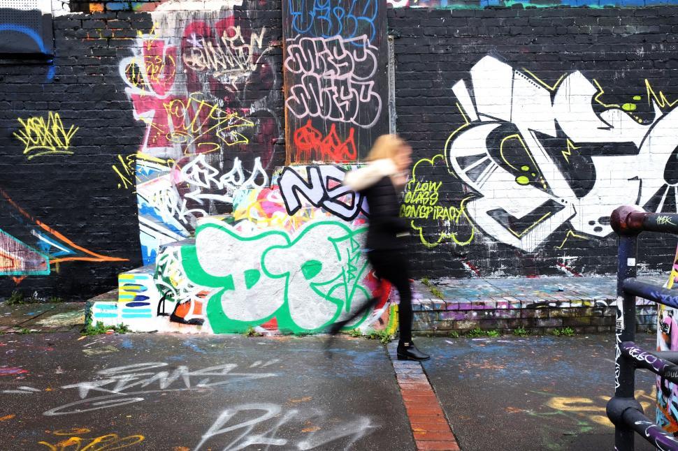 Free Image of Man Riding Skateboard Next to Graffiti Covered Wall 
