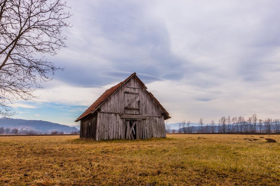 Free Image of Barn in Field With Tree in Foreground 