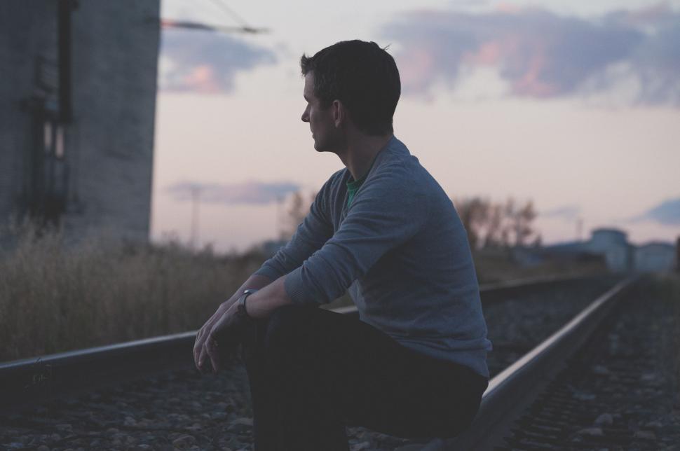 Free Image of Man Sitting on Train Track Next to Building 